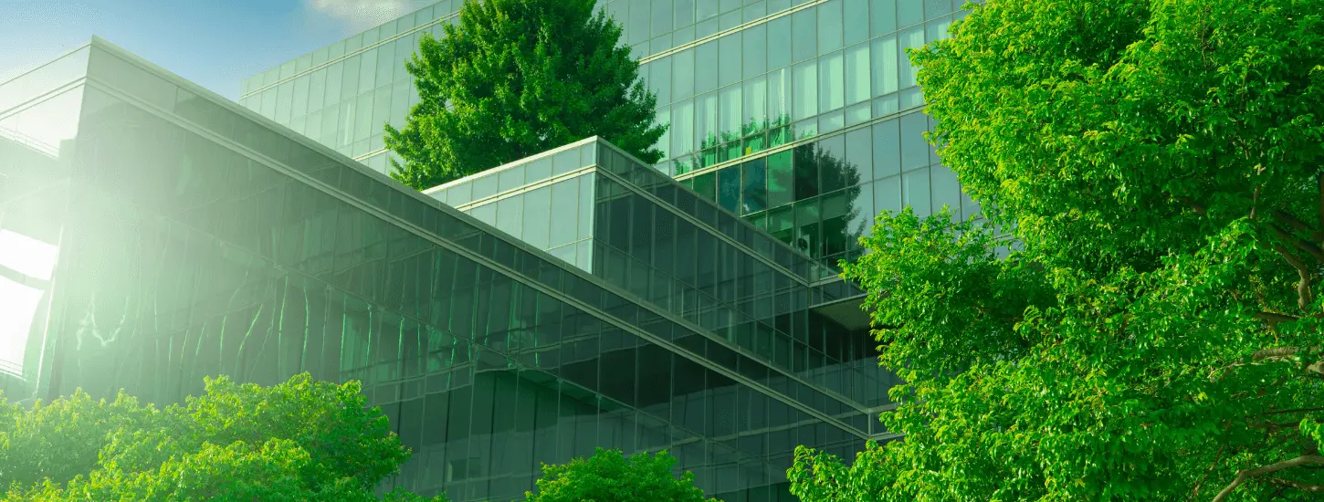 Moderna staklena zgrada među zelenim drvećem